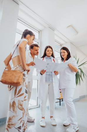 Group of doctors advising a smiling couple in a clinic, discussing medical results, pregnancy options, and successful treatment solutions.の写真素材