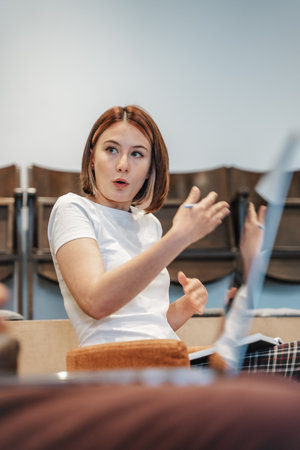 Alluring business girl gesticulating with her arms while explaining something to her colleagueの写真素材