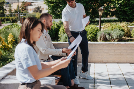 Young business people working remotely, out in the city, planning, discussing, sharing ideasの写真素材