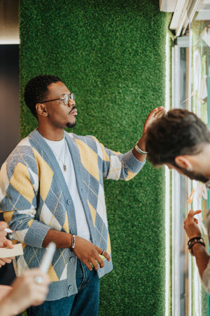 Multiracial Business Team Collaborating on Creative Ideas and Strategies in Glass-Walled Office...