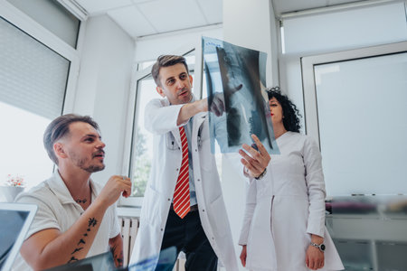 Group of young patient at clinic. Doctors discussing x-ray. Specialists providing successful treatment and recovery.の写真素材