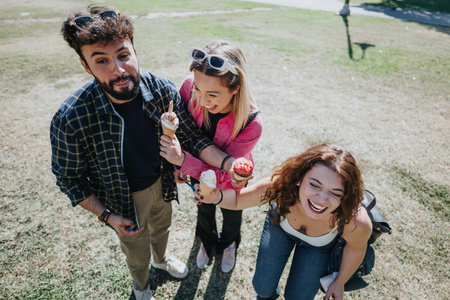 Carefree friends enjoying a sunny day in the park, eating ice cream and having fun together.