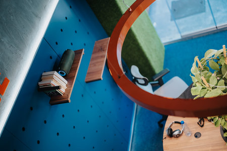 Small bookshelf on the wall, books and speaker with music on it. High angle view.