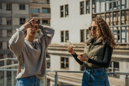 Brunette girl fixing her hair while her curly haired friend is holding her hair clip