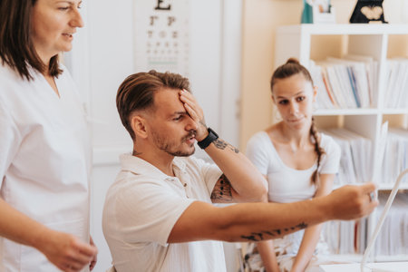 Experienced ophthalmologist checking eyesight and hearing in hospital room with a group of patients...