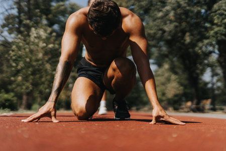 Man preparing to run on a race track in the park. Sports man in a starting running position.