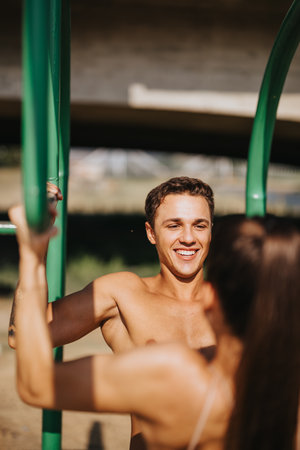 Caucasian friends challenge muscles on bars, doing pull-ups. Exercising outdoors, they train and prepare for fitness goals.の写真素材