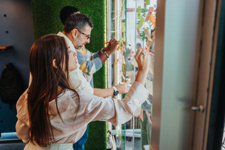 They share ideas, write on sticky notes, and show teamwork in a dynamic corporate environment.の写真素材