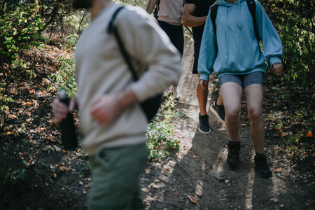 Friends hiking through a lush forest, enjoying an active conversation in the mountains.