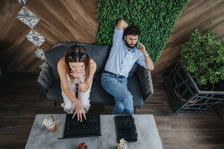 Top view shot of young couple working together remotely in an urban coffee bar at the center of the...