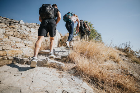 Athletic friends enjoy hiking on a sunny day in the forest. They breathe fresh air, explore nature, and exercise while having fun and conversations.の写真素材