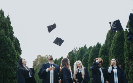 Graduates in caps and gowns celebrate their achievement, sharing happiness and creating positive memories in the sunny park.の写真素材