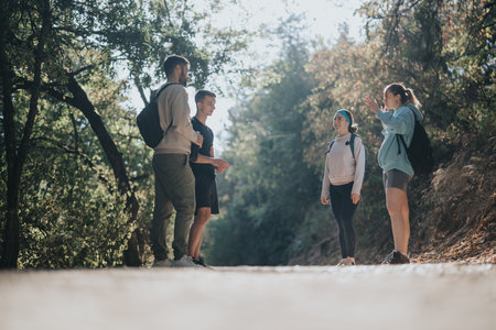A group of athletic friends enjoy a sunny day hiking through a green forest, exploring nature, and having fun conversations.の写真素材