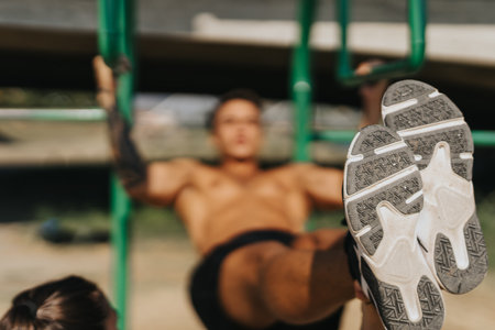 Fit friends challenge each other, doing pull ups on metal bars in the park. They warm up, stretch...