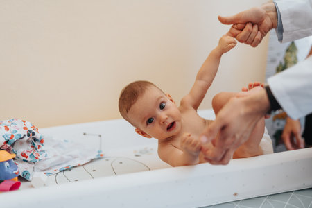 Little baby in diaper looking at camera. Doctor playing with little baby.の写真素材