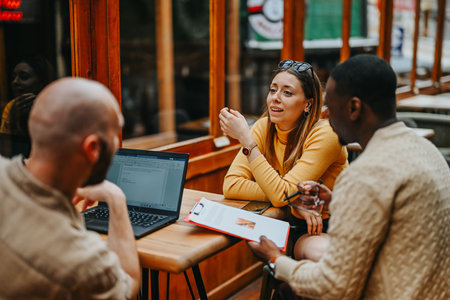 Young, multiracial corporate team collaborates on business ideas at a busy coffee bar, planning...