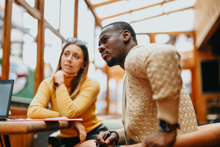Multicultural startup team strategizes for business growth, profitability, and securing funding from angel investors at a trendy coffee bar meeting.の写真素材