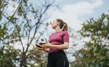 Attractive Girl Enjoying Outdoor Football Freestyling in Sunny Parkの写真素材