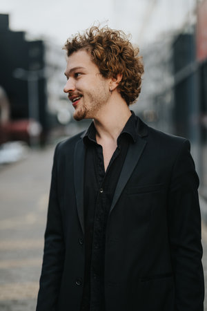 Young Successful Man Standing Outdoors, Confidently Posing for Camera with Stylish Smileの写真素材