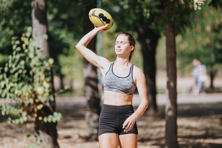Sports Girl Having Fun Outdoors in the City Park. She is Having Fun With Rugby Ball After the Training.の写真素材