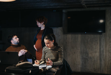 Business team collaborating on project development and sales strategy late at night in corporate office.の写真素材