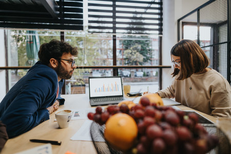Coworkers analyzing documents in a creative office, working together on market research and sales statistics for business expansion and profit growth.の写真素材