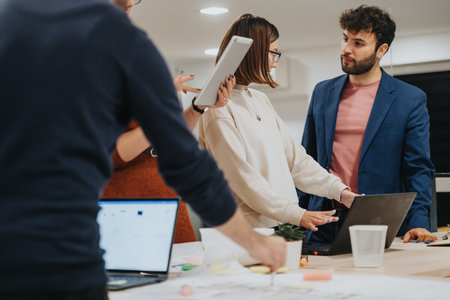 Multiracial team analyzing reports and discussing business growth in a late-night office. Colleagues working extra hours to meet project deadline.の写真素材