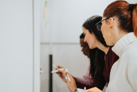 Multicultural business professionals collaborate and brainstorm in a modern office, discussing data analysis and market research, aiming for success.の写真素材