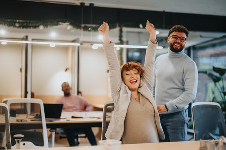 A pregnant businesswoman celebrating successful work with colleagues in an office..の写真素材