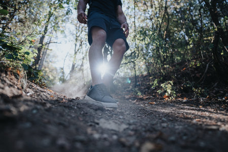 A happy hiker runs through a green forest landscape, enjoying an active day off in natures playground.の写真素材
