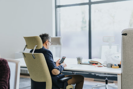 Middle-aged businessman sitting in a comfy chair checking his email during break at work.の写真素材