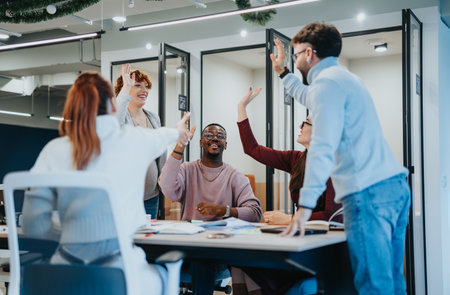 Multicultural group of businesspeople celebrating successful work completion in office. They are giving high five each other.の写真素材