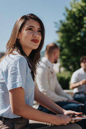 Alluring brunette businesswoman looking at something with slight smile on her face. Businesswoman working outdoorsの写真素材
