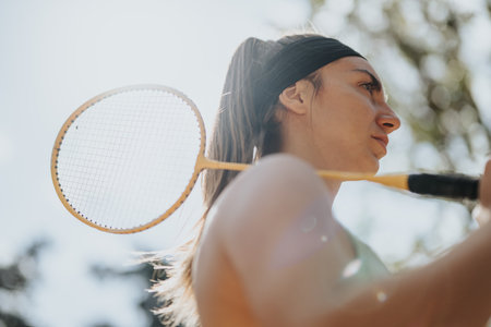 A sports, female person is holding a racket on her shoulder. Low angle view photo.の写真素材