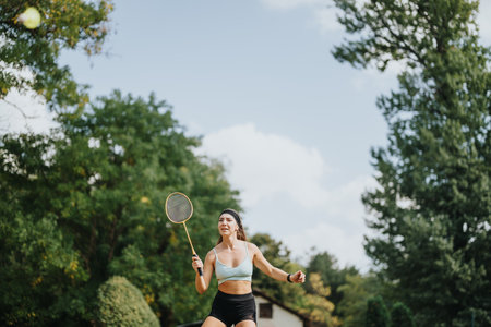 Fit and sporty girl playing badminton in a sunny park, enjoying her outdoor training with friend.
