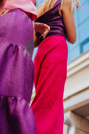 Confident ladies embrace urban city life in trendy outfits with shades of pink and purple. A perfect representation of modern street fashion.の写真素材