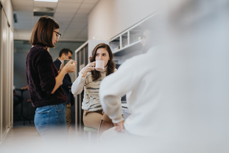 Young businesspeople in a modern kitchen, collaborating and discussing ideas, enjoying a cheerful...