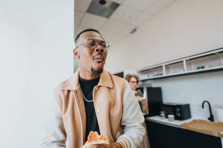A black guy navigates office dynamics, finding solace in a pizza break, a slice of delight adding a flavorful twist to the daily professional rhythm.の写真素材