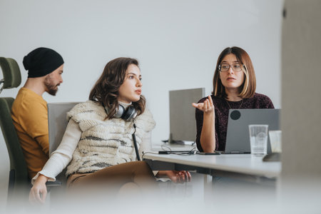 Young colleagues collaborating on a project in a corporate office, discussing strategies and working towards profitability and sustainability.の写真素材