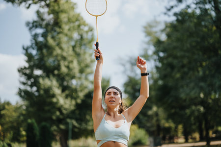 Attractive Young Woman Playing Badminton in a Sunny Park in the City.の写真素材