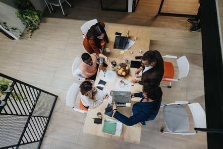 A diverse group of professionals collaboratively discussing business strategies and analyzing market data in a creative office environment.の写真素材
