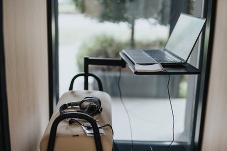 Phone booth setup: seating, small desk, laptop, a mobile workspace.の写真素材