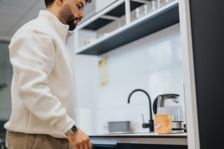 Male employee prepared himself a tea. He is taking a break from work.の写真素材