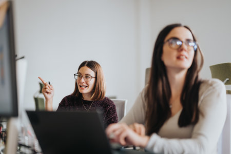 Female company employees discussing digital marketing strategies in a corporate office.の写真素材