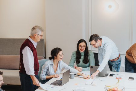 Group of male and female coworkers collaborate at a meeting in a bright contemporary office space, indicating teamwork, strategy, and engagement.の写真素材