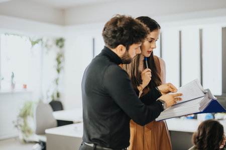 Focused business colleagues reviewing documents together in a bright modern office spaceの写真素材