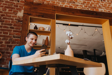 Smart and Happy Teenager Enjoying Coffee and Relaxing at a Sunny Cafe Bar After Schoolの写真素材