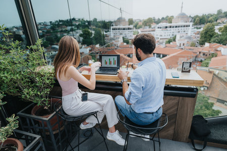 Young business couple discussing new projects and market expansion ideas over coffee in an urban cafe.の写真素材