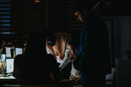 Business team working late at night, collaborating on project deadlines, analyzing reports, and discussing strategies for growth and profitability.の写真素材