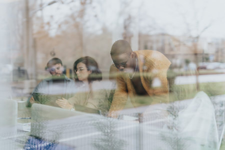 Multiethnic business coworkers collaborating and discussing reports in a creative office, planning for business expansion and profit growth.の写真素材